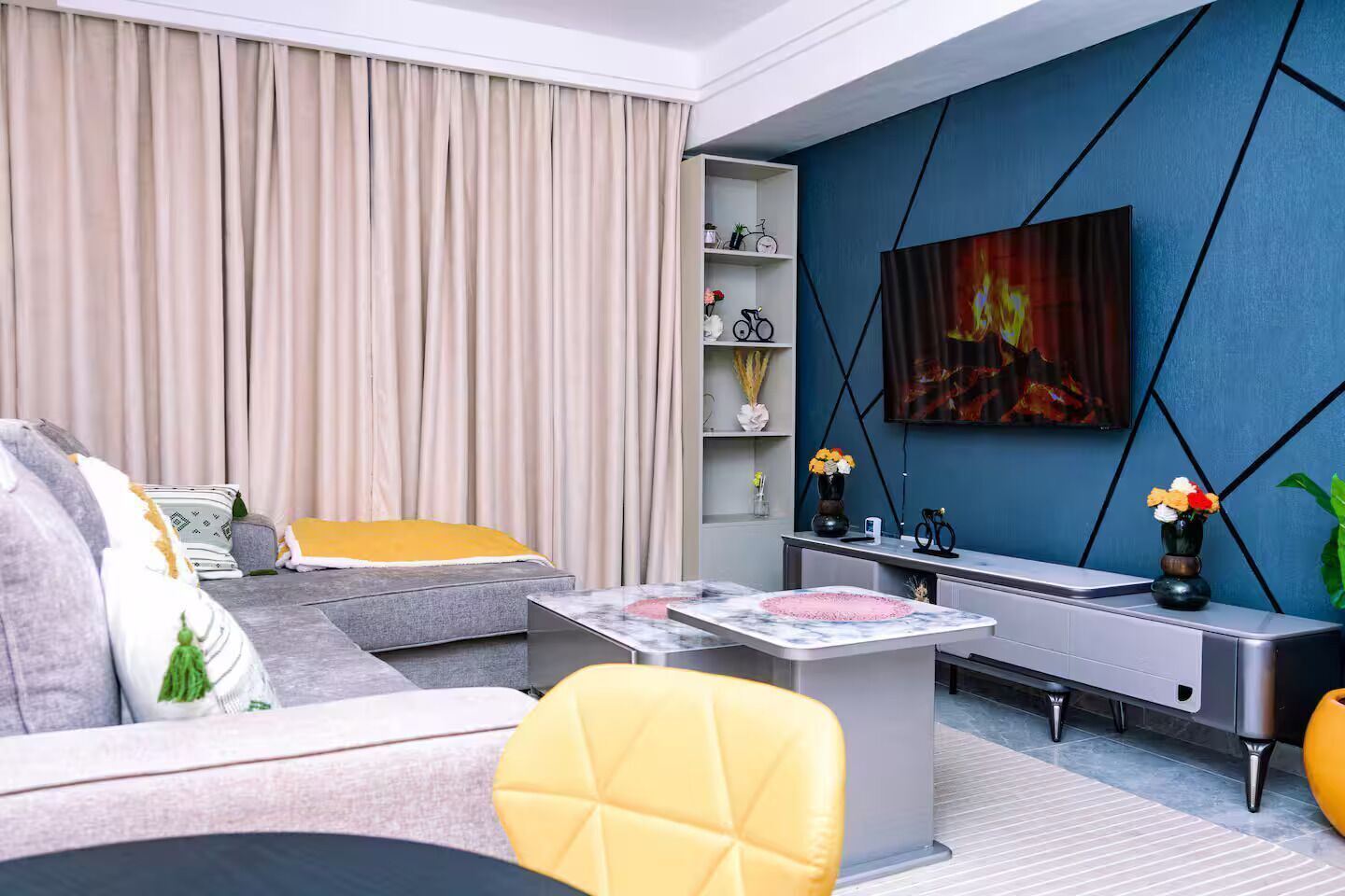 A modern living room with a sofa, a coffee table, and a TV mounted on a blue wall.