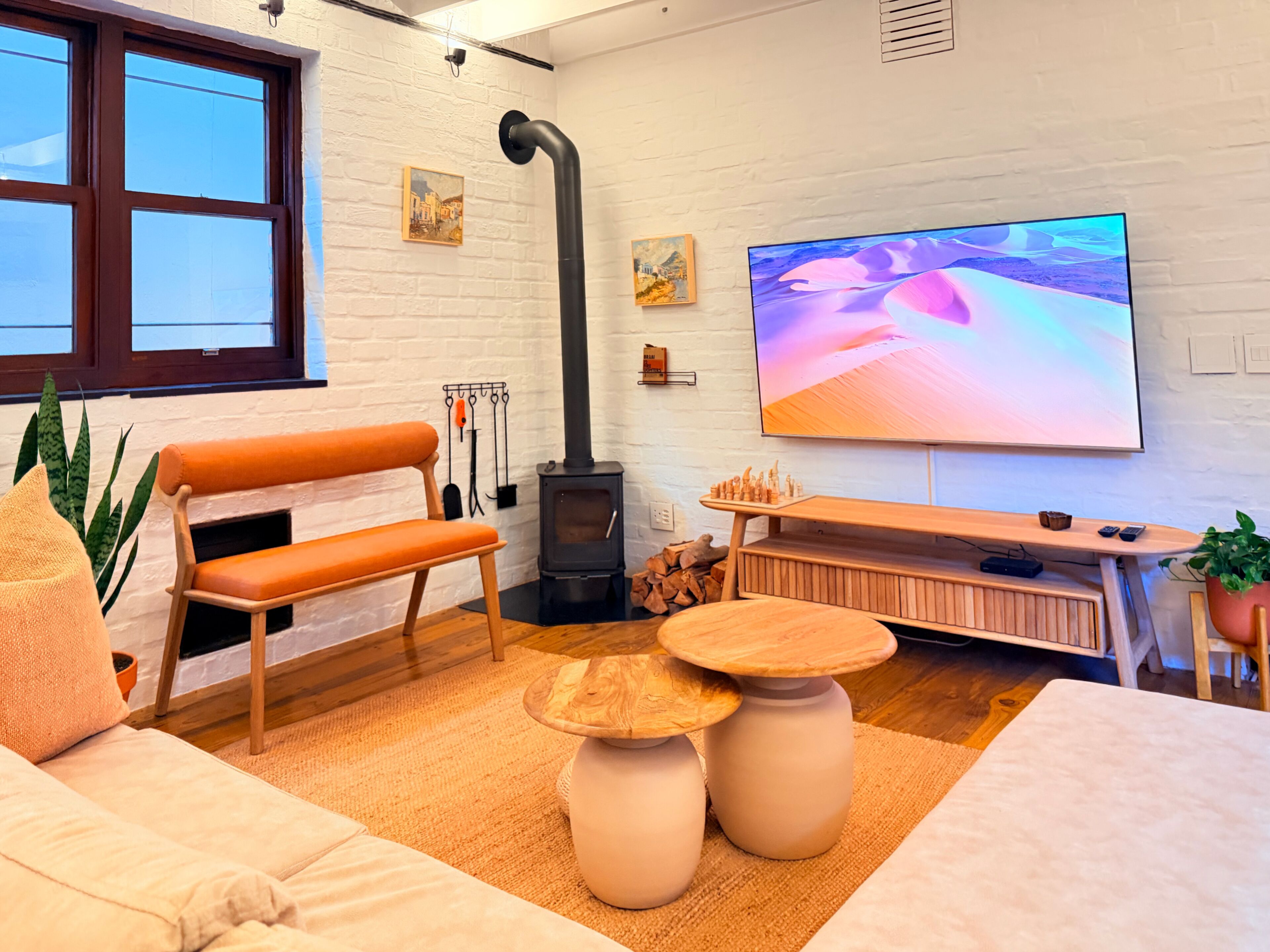 Ett modernt vardagsrum med en soffa, en tv, en öppen spis och ett stort fönster.
