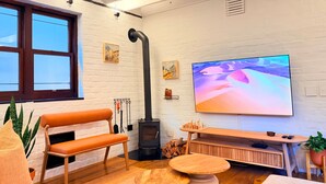 Ett modernt vardagsrum med en soffa, en tv, en öppen spis och ett stort fönster.