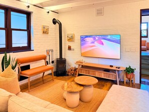 Ett mysigt vardagsrum med en soffa, en tv, en öppen spis och ett stort fönster.