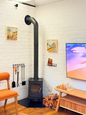 A cozy room with a wood-burning stove, a painting, a mounted television, and a chessboard. - Curated sanctuary in the heart of the city (Cape Town)