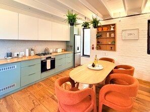 A modern kitchen with light blue cabinets, a wooden countertop, and a dining table with orange chairs. - Curated sanctuary in the heart of the city (Cape Town)