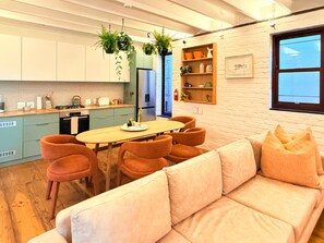 A modern kitchen with a dining area, featuring a sofa and chairs, a table, and hanging plants. - Curated sanctuary in the heart of the city (Cape Town)