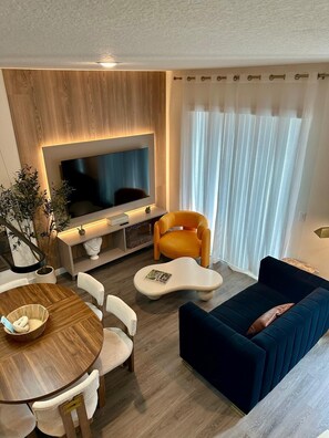 Una sala de estar moderna con televisor, sofá y comedor.