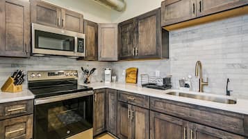A modern kitchen with dark wood cabinets, stainless steel appliances, and a white countertop.