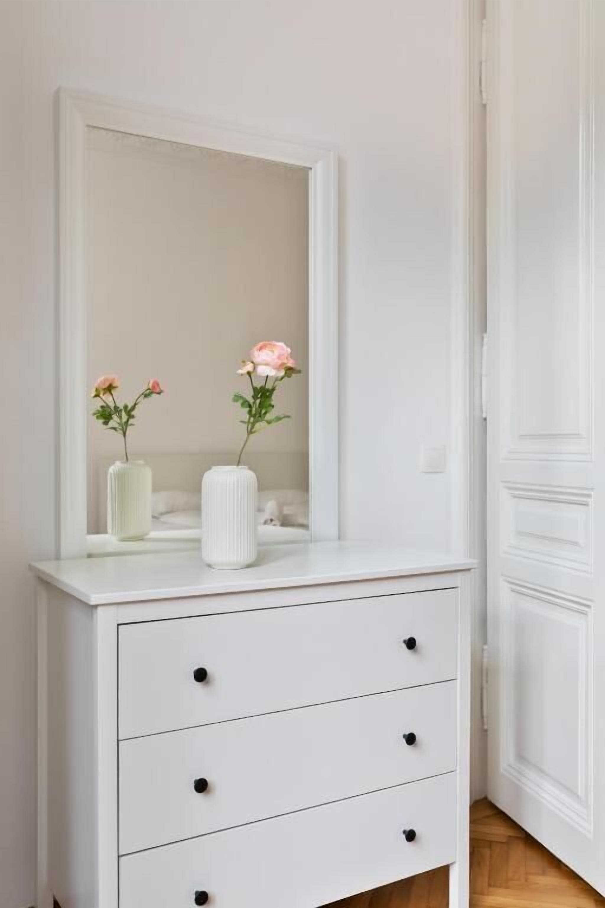 A white dresser with three drawers and a mirror above it.