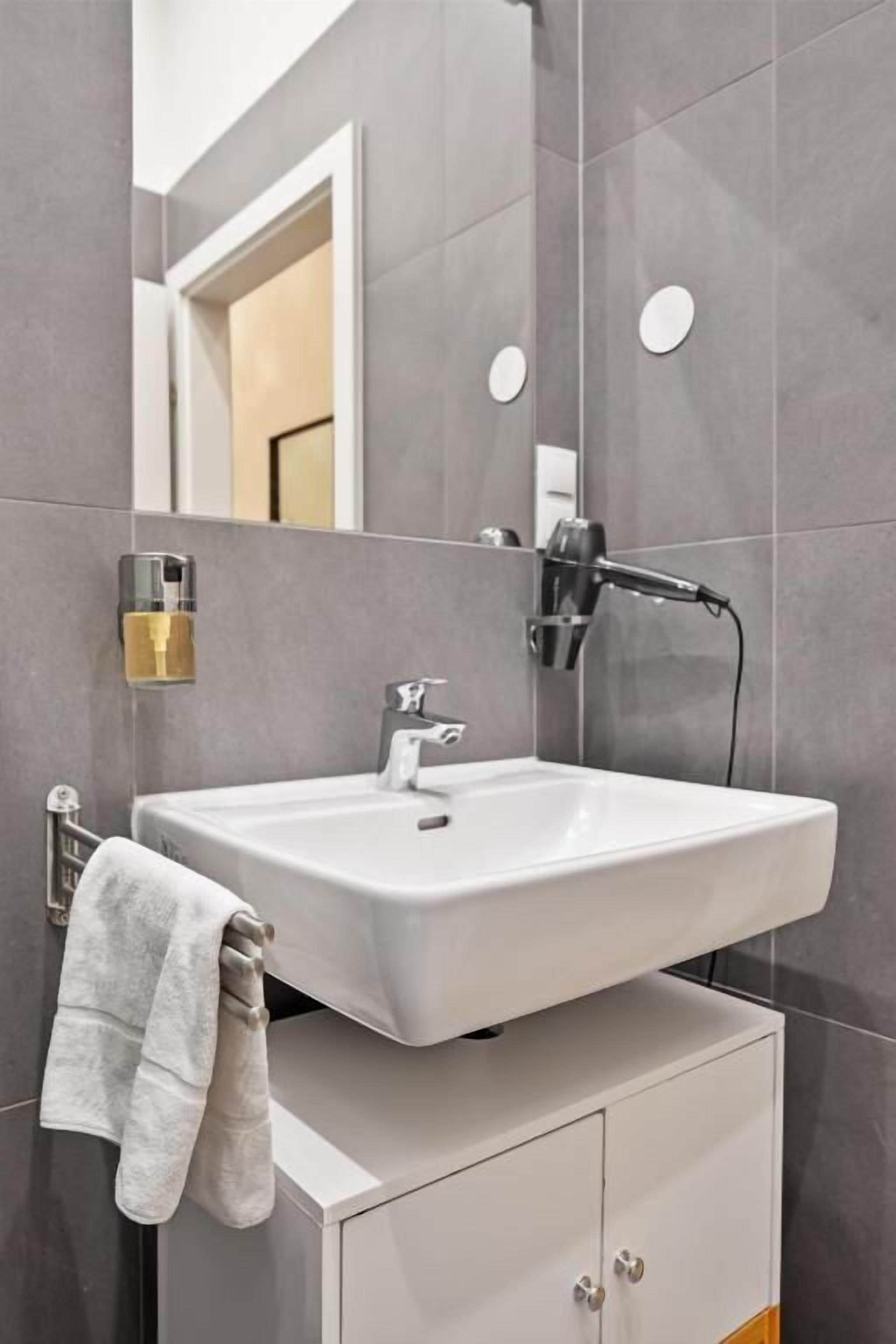 A bathroom with a white sink, a towel rack, and a mirror.