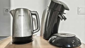 Una tetera de acero inoxidable y una cafetera negra sobre una encimera de madera.