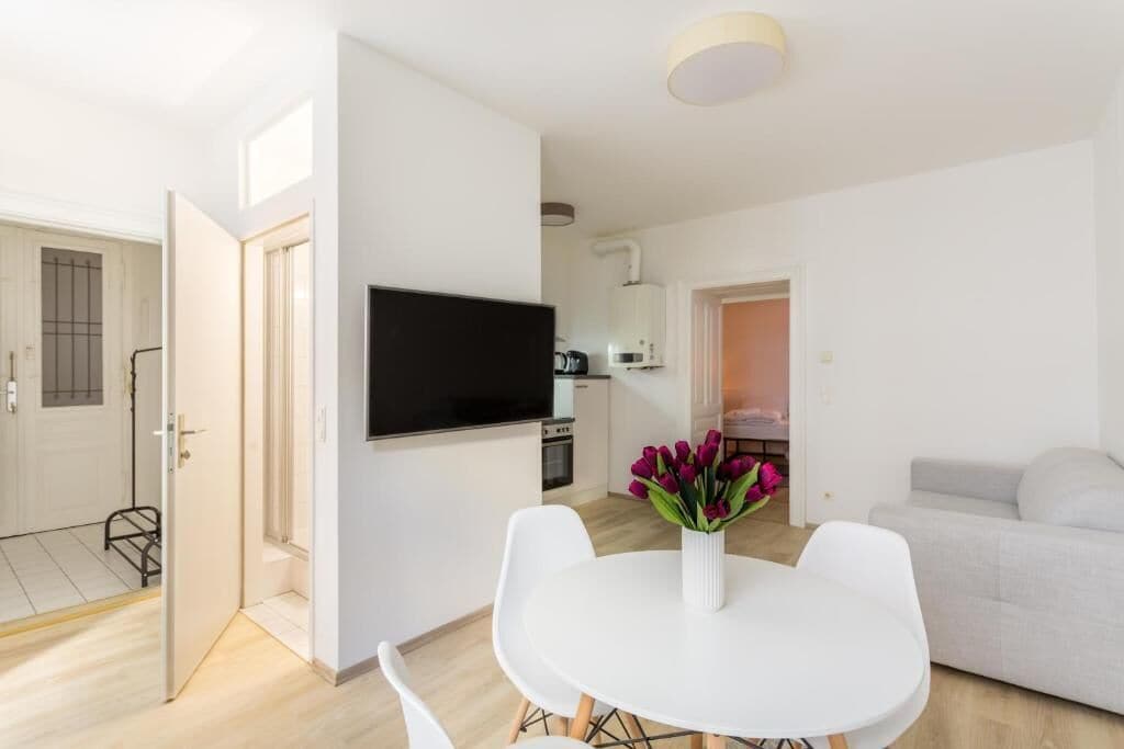 Una sala moderna con una televisión de pantalla plana, una mesa de comedor con sillas y un sofá.