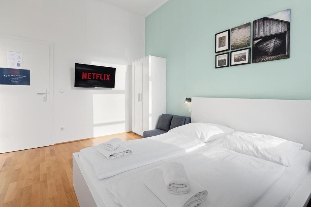 Habitación de hotel con una cama, un televisor montado en la pared y una puerta con un cartel.