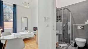 A modern hotel room with a bed, a desk, a shower, and a toilet. - Cityswap- Wien Naschmarkt (Wien)
