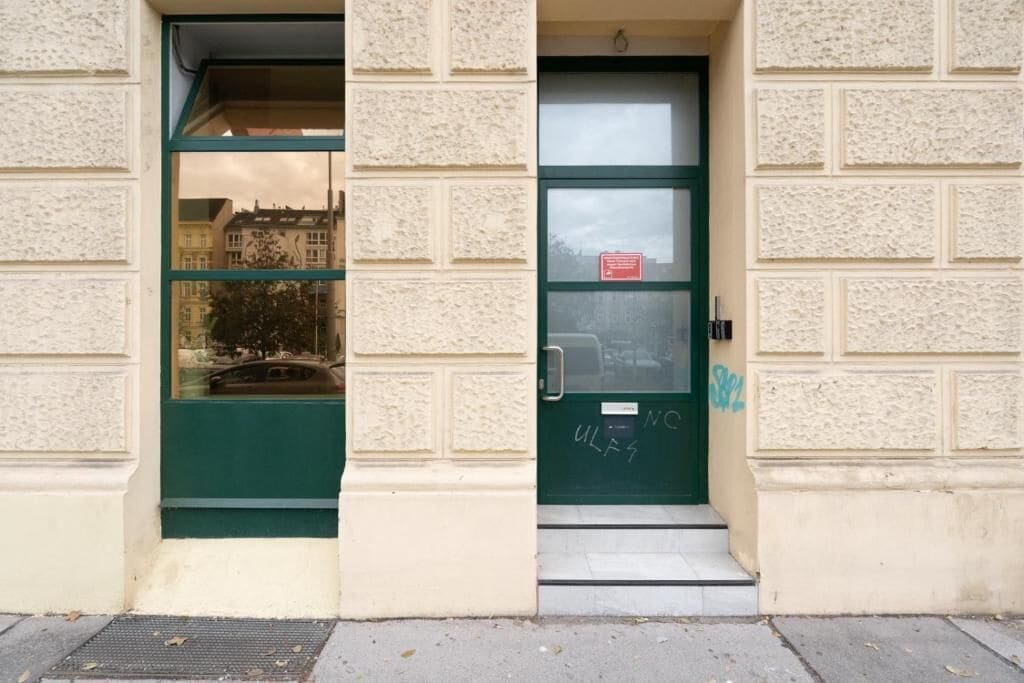 Une entrée d’immeuble avec une porte verte et une fenêtre.