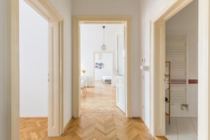 A hallway with a herringbone floor leading to a room with a white door. - Cityswap- Wien Naschmarkt (Wien)