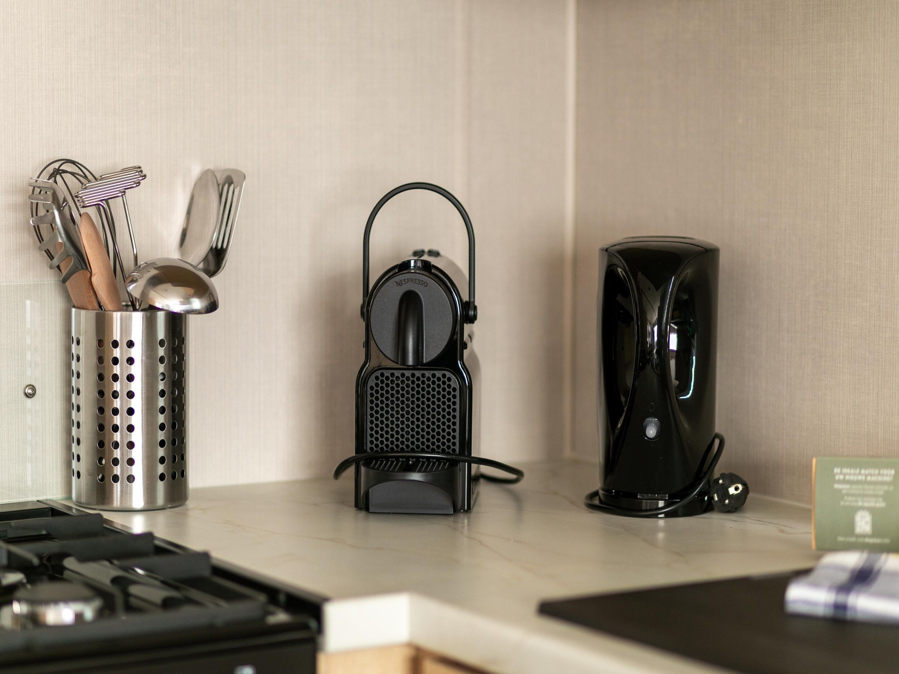 A kitchen counter with a coffee machine, a utensil holder, and a stove.