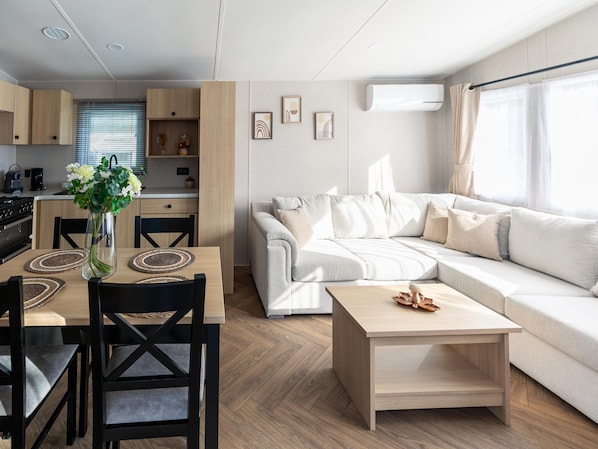 Una sala de estar moderna con un sofá, una mesa de comedor con sillas y una cocina al fondo.
