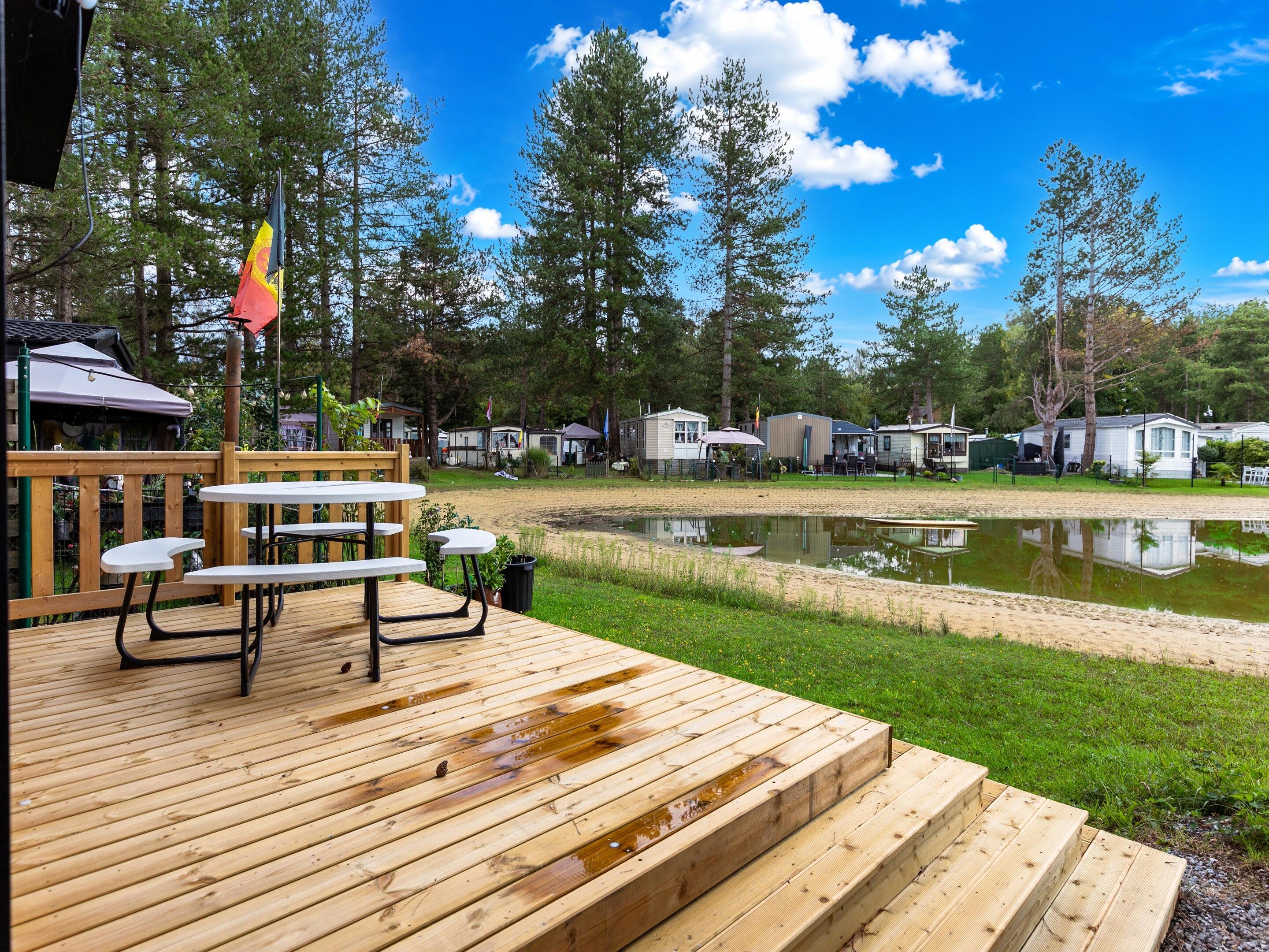 A wooden deck with picnic tables and a pond.
