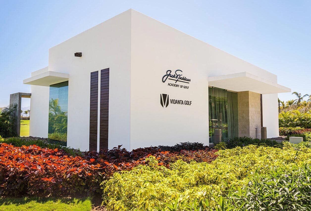 A modern building with a white facade, featuring the Jack & Jillous Academy of Golf and Vidanta Golf logos.