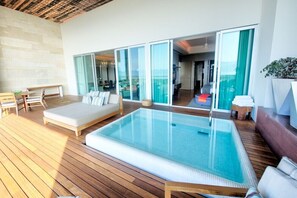 A modern outdoor pool area with a wooden deck, a lounge chair, and a glass-enclosed living space. - SPECTACULAR 3 BR SUITE WITH PLUNGE POOL IN 5 DIAMOND RESORT NUEVO VALLARTA JD (las jarretaderas)