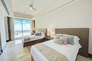 A hotel room with two beds, a ceiling fan, a large window with curtains, and a view of the outdoors. - SPECTACULAR 3 BR SUITE WITH PLUNGE POOL IN 5 DIAMOND RESORT NUEVO VALLARTA JD (las jarretaderas)