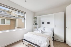 A bedroom with a bed, a window, a wardrobe, and a shelf with items. - The Dandy Relaxed Living near St Kilda Beach and CBD (Caulfield North)