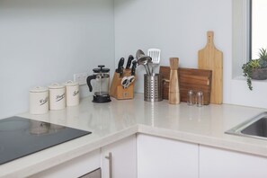 A kitchen with a modern design, featuring a coffee maker, utensils, and a wooden cutting board. - The Dandy Relaxed Living near St Kilda Beach and CBD (Caulfield North)