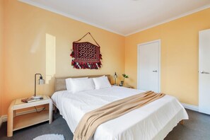 A hotel room with a bed, bedside tables, a wall hanging, and a door. - Coral Atelier Bright Artistic Hideaway in the CBD (Melbourne)