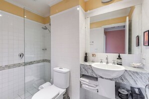 A modern bathroom with a glass-enclosed shower, a white toilet, a marble sink, and a large mirror. - Coral Atelier Bright Artistic Hideaway in the CBD (Melbourne)