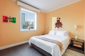 A hotel room with a bed, a window with a city view, a wall with a motivational sign, and a decorative wall hanging. - Coral Atelier Bright Artistic Hideaway in the CBD (Melbourne)