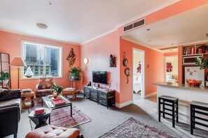 A living room with a sofa, TV, and decorative items. - Coral Atelier Bright Artistic Hideaway in the CBD (Melbourne)