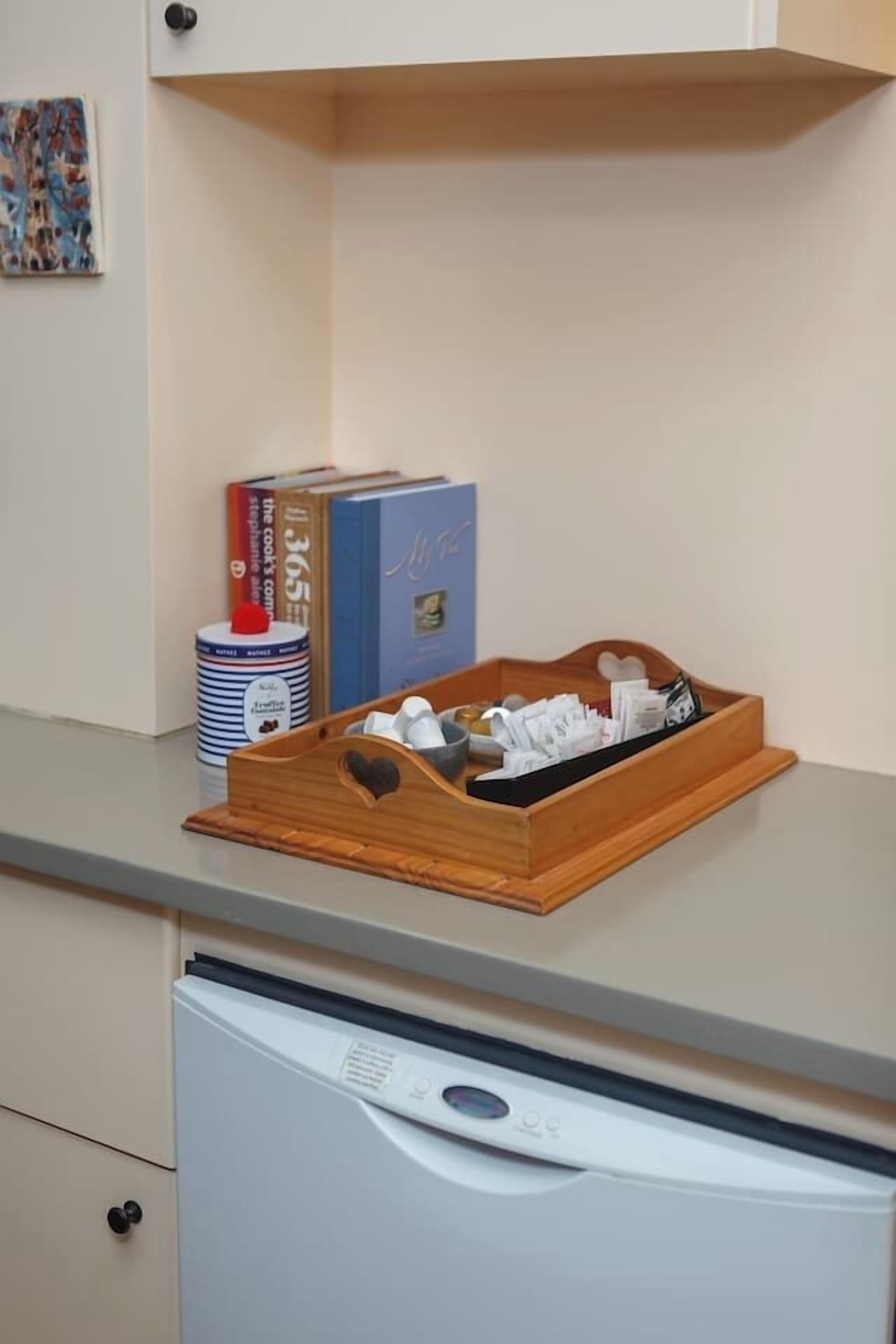 Una encimera de cocina con una bandeja de madera que contiene utensilios, un recipiente y un libro de cocina.