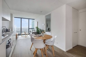 A modern kitchen with a dining area, large windows, and a view of the city. - A Sky high Metropolis Retreat near the CBD (Southbank)