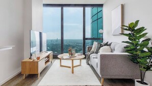 Una sala de estar moderna con un ventanal grande, un sofá, una mesa de centro y un televisor.