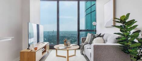 A modern living room with a large window, a sofa, a coffee table, and a TV.