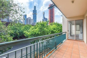 Ein Balkon mit Blick auf die Stadt, ein Fliesenboden und eine Tür zu einem Innenraum.