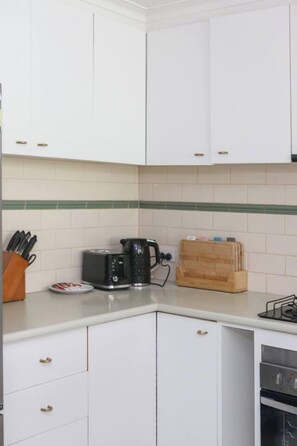 Eine Küche mit weißen Schränken, einem Toaster, einem Wasserkocher und einem Gewürzregal.