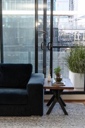 Un saló modern amb un sofà fosc, una taula de centre de fusta i una planta en test.