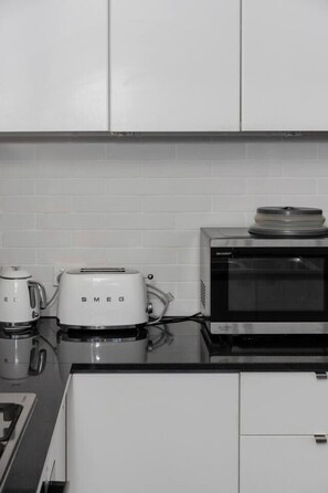 A kitchen with white cabinets, a microwave, a toaster, and a coffee maker. - Sentinel Vista Urban Stay with Pool and Tennis Court (Southbank)