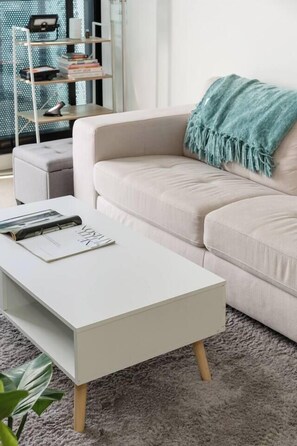 Ein modernes Wohnzimmer mit einem weißen Sofa, einem weißen Couchtisch und einem Bücherregal.