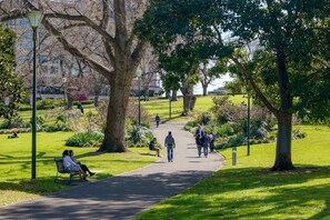 A park with a paved walkway, benches, and trees. - West Edge Urban Outlook near Gardens and Markets (West Melbourne)