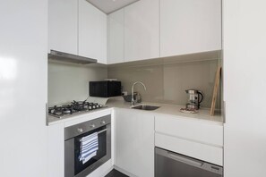 Eine kompakte Küche mit Gasherd, Backofen, Mikrowelle, Spüle und Geschirrspüler.