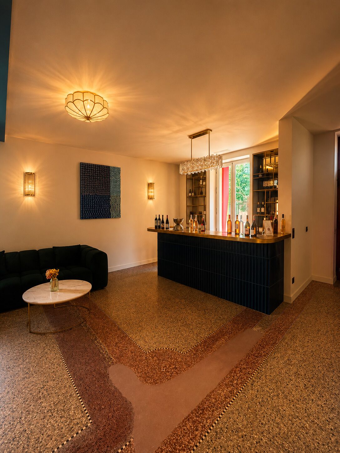 A modern living room with a dark-colored sofa, a round coffee table with a vase, a bar area with bottles, and a patterned rug.