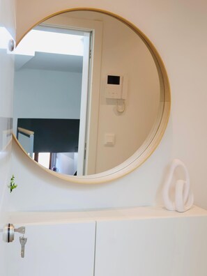 Ein Badezimmer mit einem runden Spiegel, einem weißen Waschbecken und einem an der Wand befestigten Telefon.