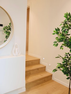A staircase with wooden steps, a white wall, and a potted plant.