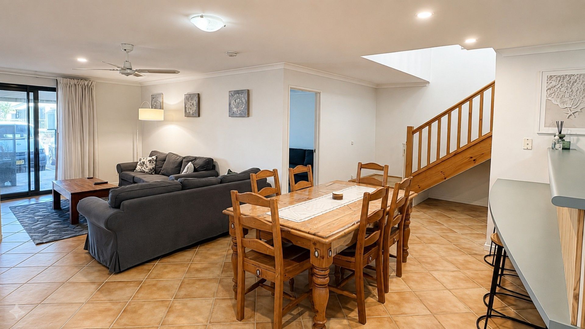 Una sala de estar moderna con un sofá, una mesa de comedor y una escalera.