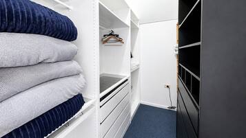 A walk-in closet with shelves, a hanging rod, and a dark-colored door.