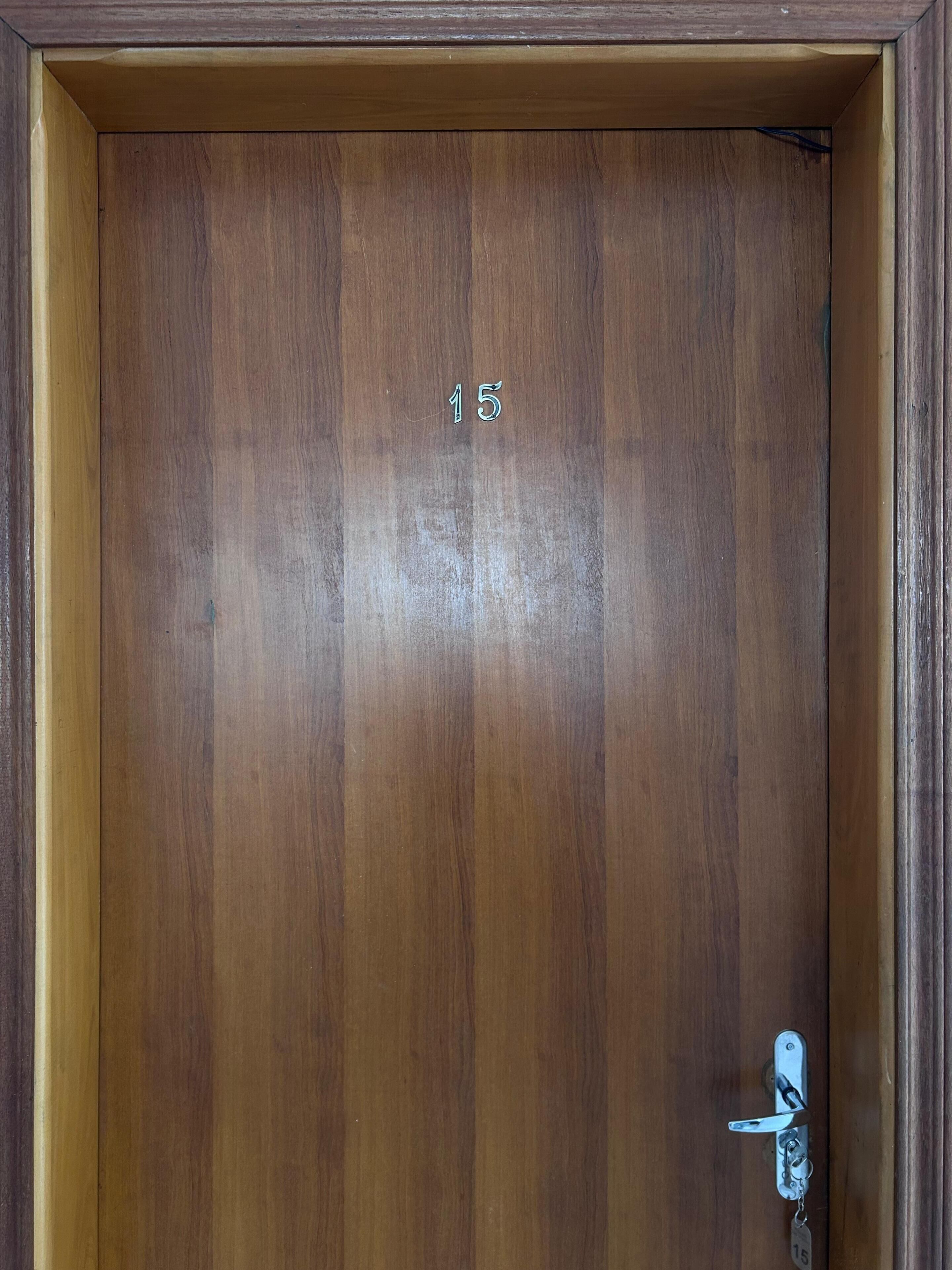 Una puerta de madera con teclado numérico y el número '15' visible.