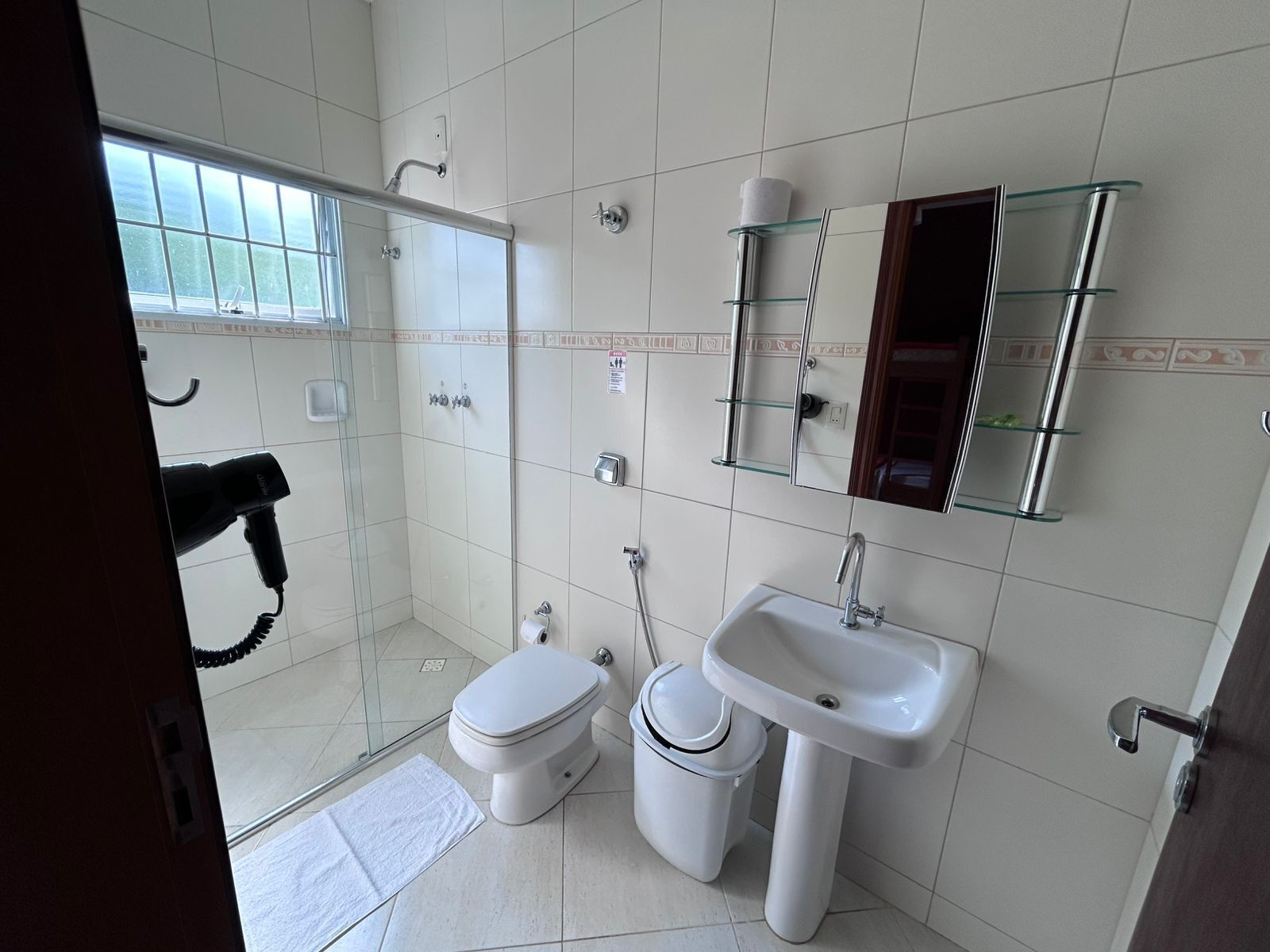 Un baño con cabina de ducha de vidrio, lavamanos blanco y un inodoro.