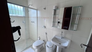 A bathroom with a glass shower enclosure, a white sink, and a toilet.