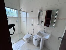 Un baño con cabina de ducha de vidrio, lavamanos blanco y un inodoro.