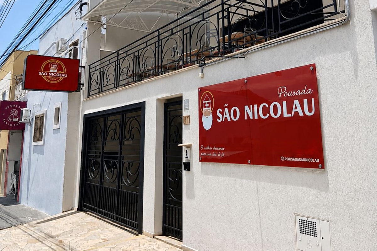 Un edificio con un letrero rojo que dice 'SÃO NICOLAU' y un balcón con barandilla de metal.